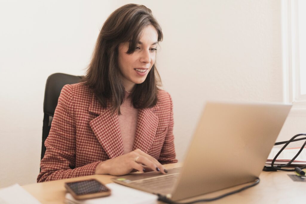 Concentrated young lady using laptop and sitting at table